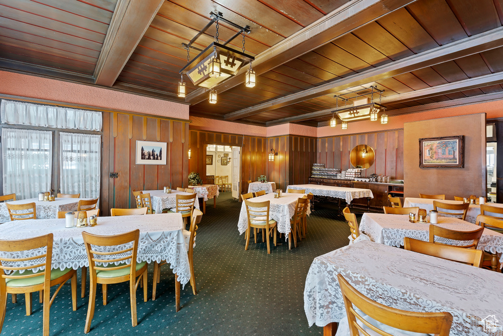 Dining room featuring beamed ceiling, wood ceiling, carpet floors, and wooden walls