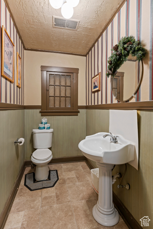 Bathroom featuring toilet, tile floors, and a textured ceiling