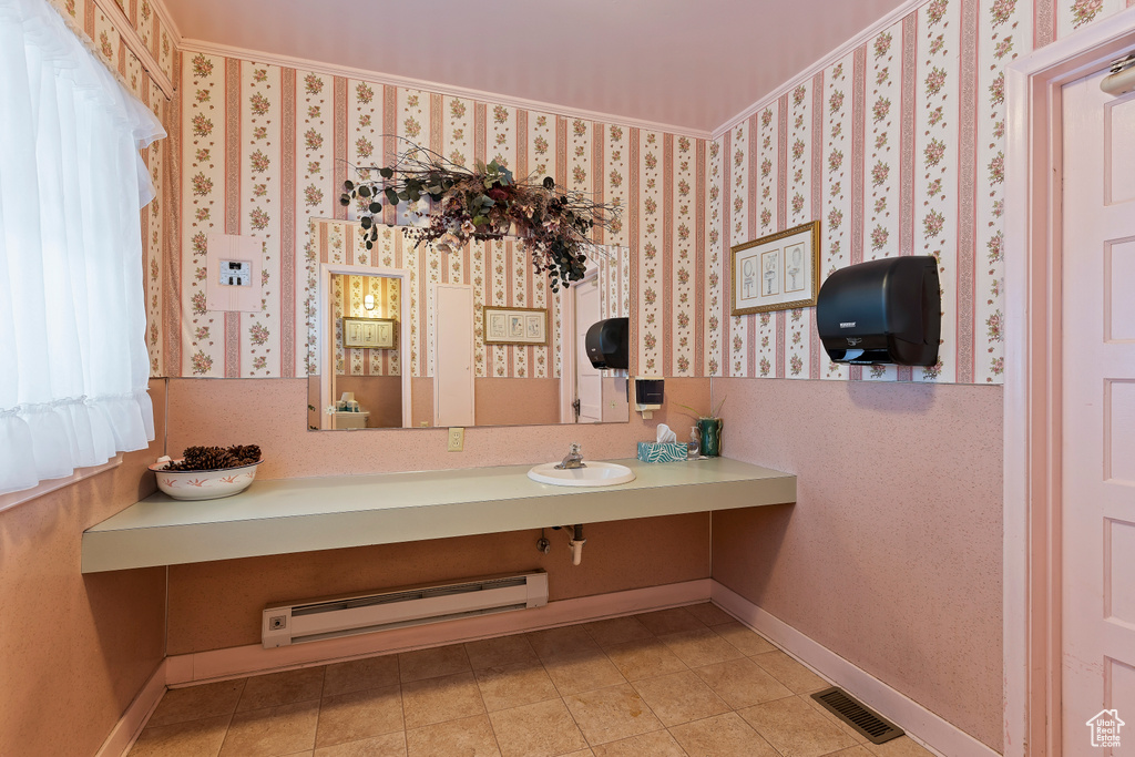 Bathroom with vanity with extensive cabinet space, a baseboard heating unit, and tile floors