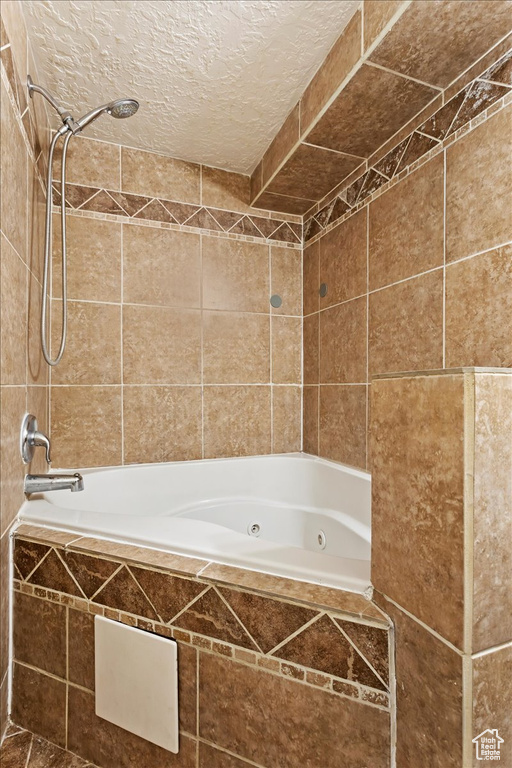 Bathroom featuring a textured ceiling, tiled shower / bath combo, and tile walls