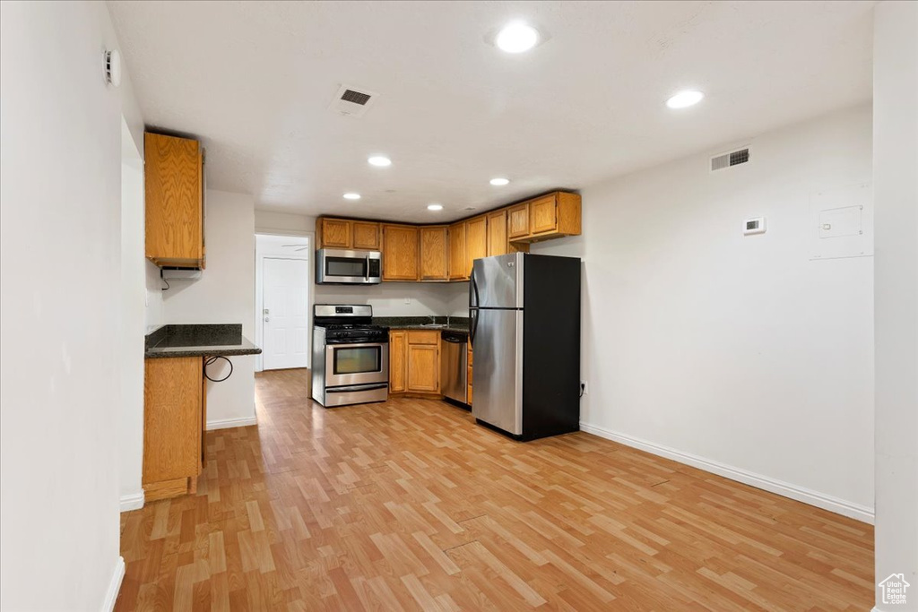 Kitchen with light hardwood / wood-style floors, appliances with stainless steel finishes, and a breakfast bar area