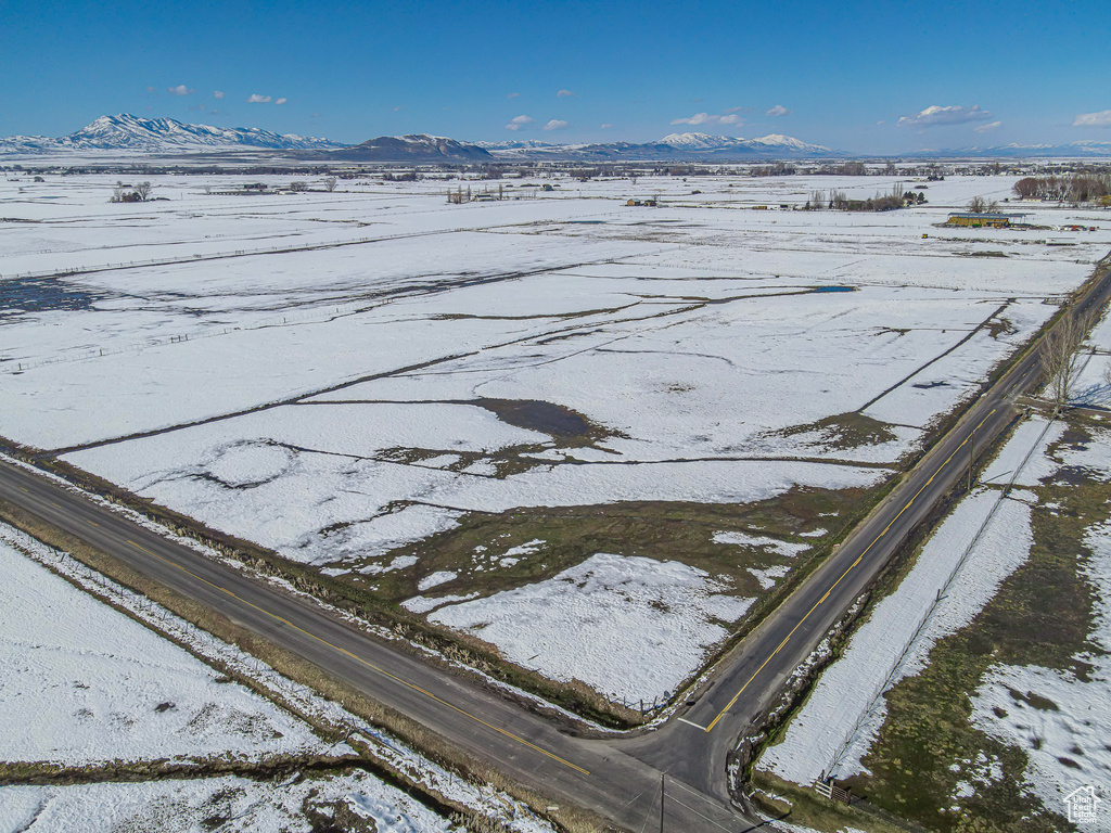Snowy aerial view featuring a mountain view and a rural view