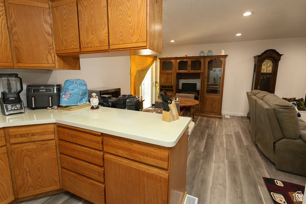 Kitchen with kitchen peninsula, hardwood / wood-style flooring, and backsplash