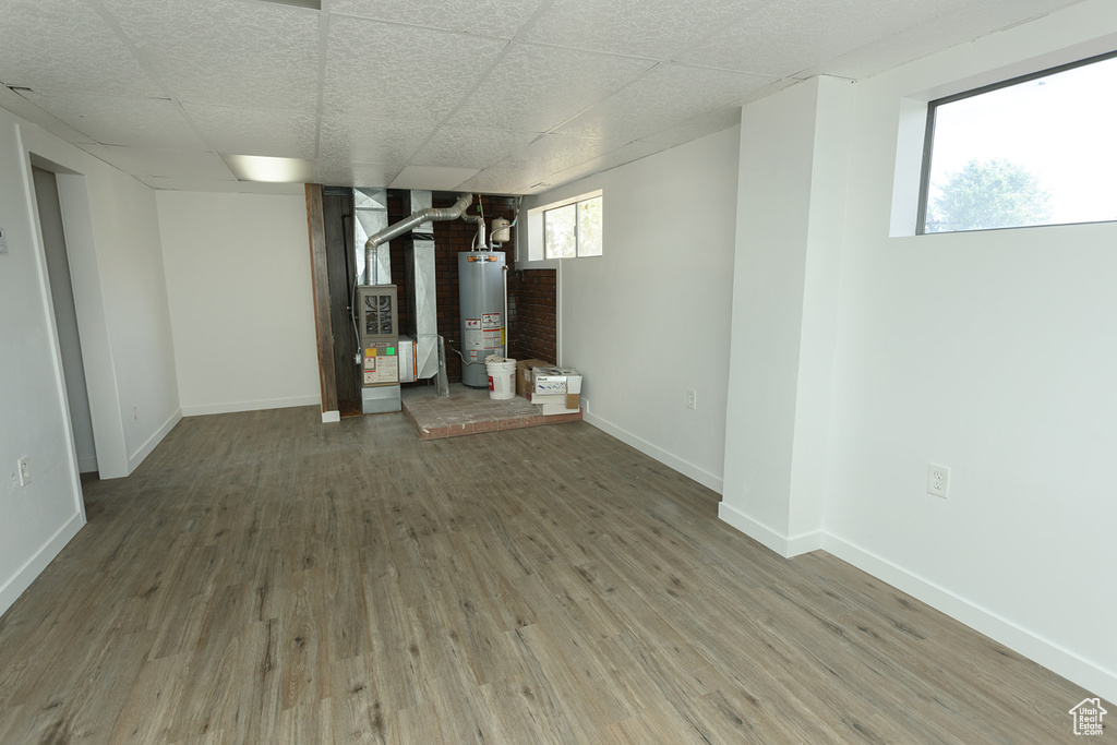 Basement featuring hardwood / wood-style floors, gas water heater, a drop ceiling, and a healthy amount of sunlight