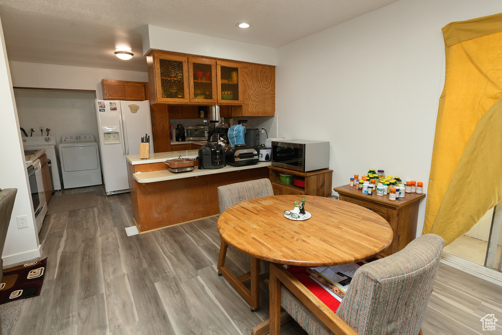 Kitchen featuring washer and dryer, hardwood / wood-style flooring, and white fridge with ice dispenser
