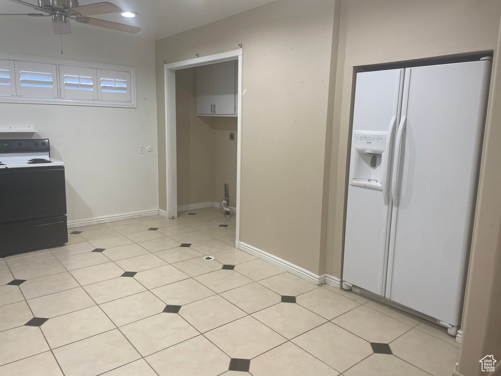 Kitchen featuring light tile flooring, white refrigerator with ice dispenser, ceiling fan, and washer / clothes dryer