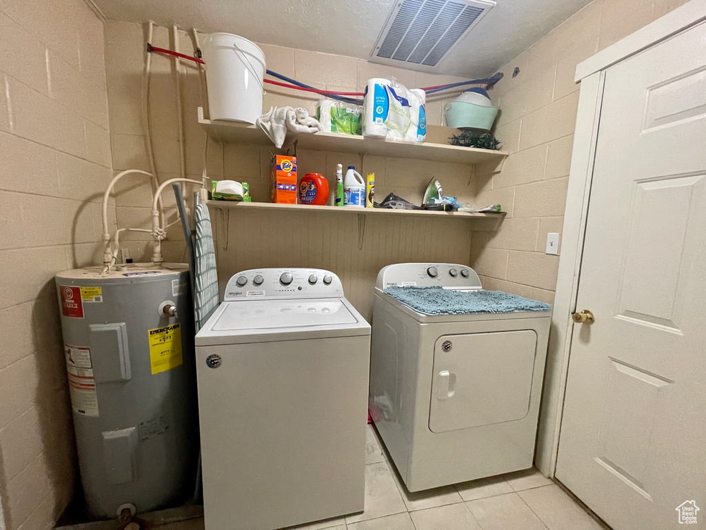 Washroom with washer and clothes dryer, light tile floors, and electric water heater