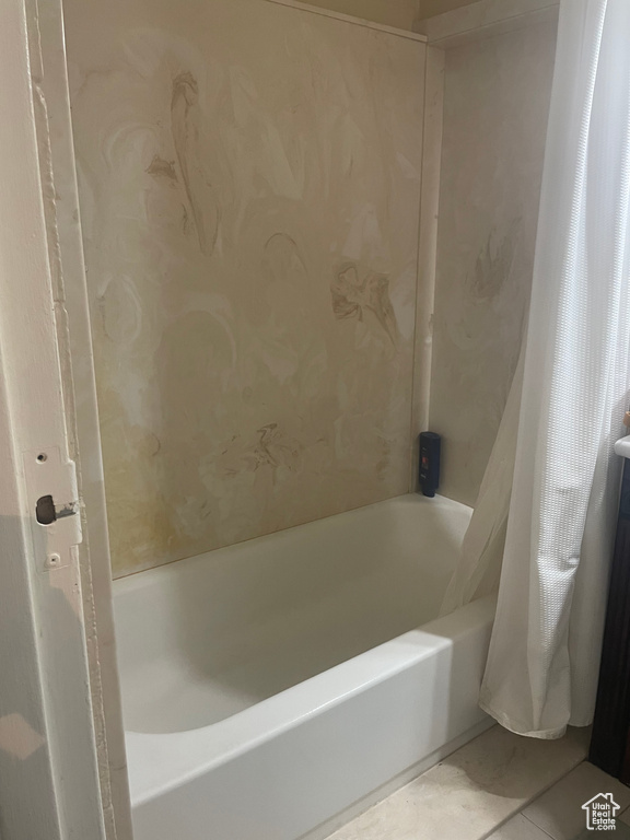 Bathroom with tile floors and shower / bathtub combination with curtain