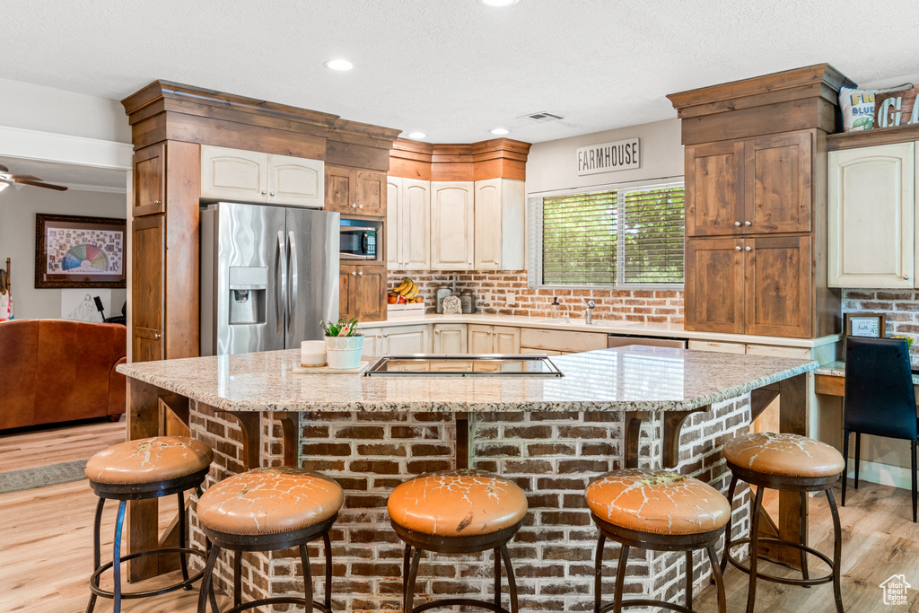 Kitchen featuring a breakfast bar area, ceiling fan, a kitchen island, and stainless steel appliances