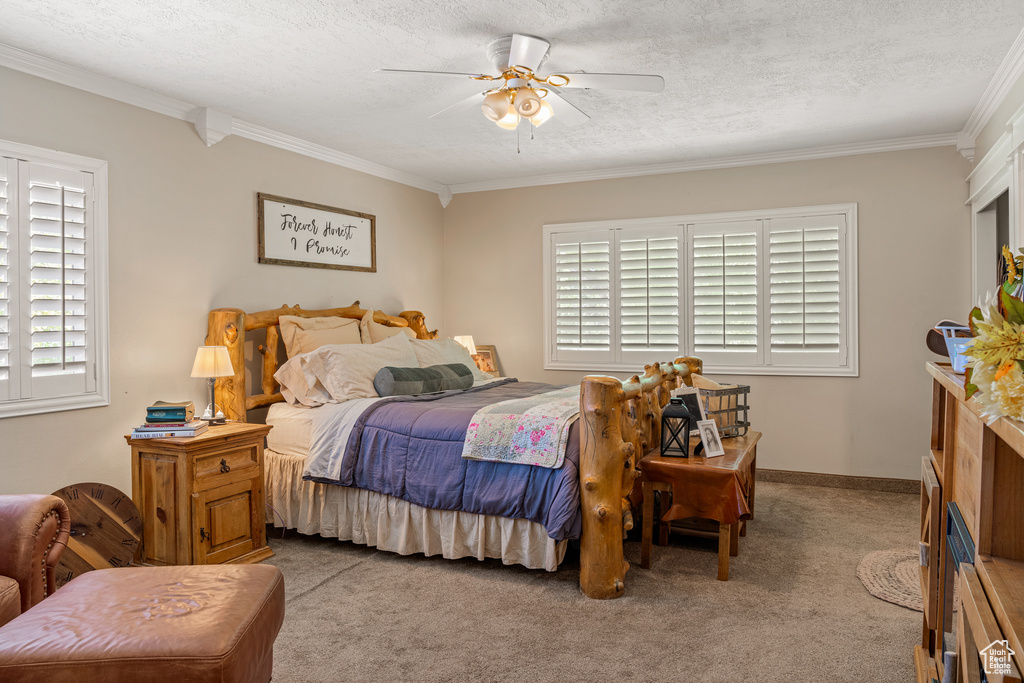 Bedroom featuring ceiling fan, light colored carpet, ornamental molding, and a textured ceiling