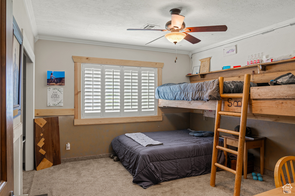 Bedroom featuring light carpet, crown molding, ceiling fan, and a textured ceiling