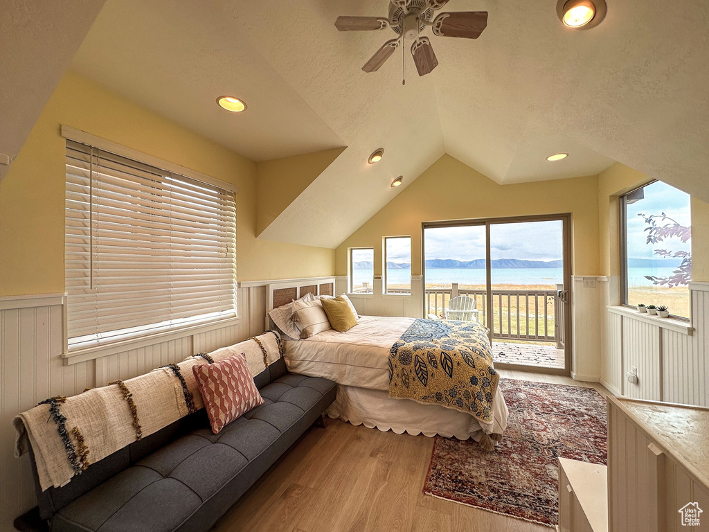 Bedroom with light hardwood / wood-style flooring, a water view, ceiling fan, lofted ceiling, and access to outside