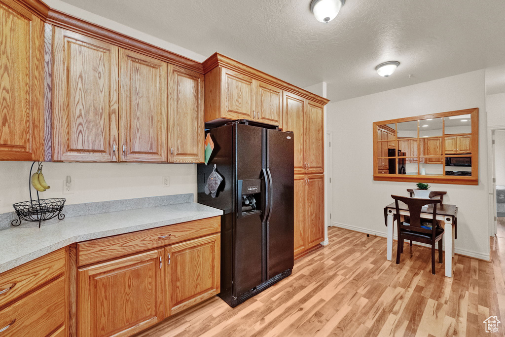 Kitchen featuring a textured ceiling, black appliances, and light hardwood / wood-style floors