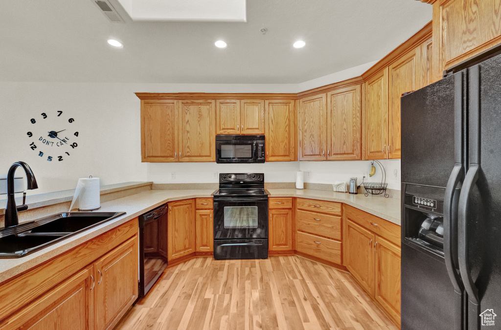 Kitchen featuring sink, black appliances, and light hardwood / wood-style floors