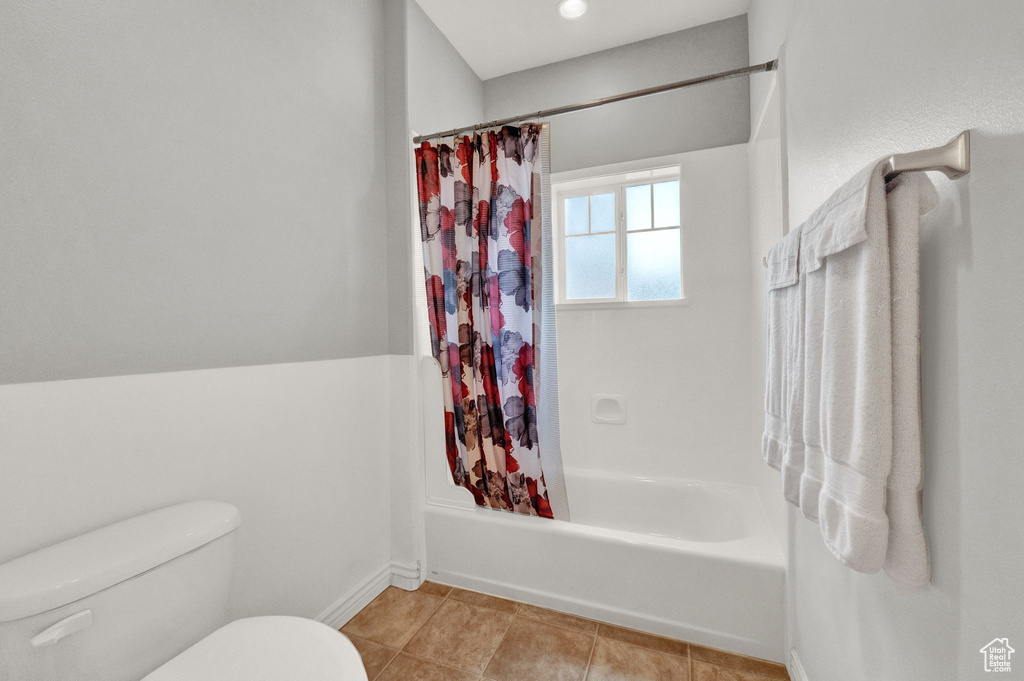 Bathroom featuring shower / tub combo with curtain, tile flooring, and toilet