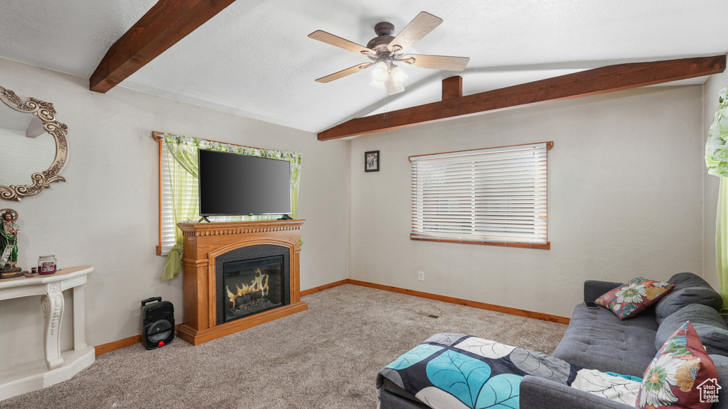 Carpeted living room featuring vaulted ceiling with beams and ceiling fan