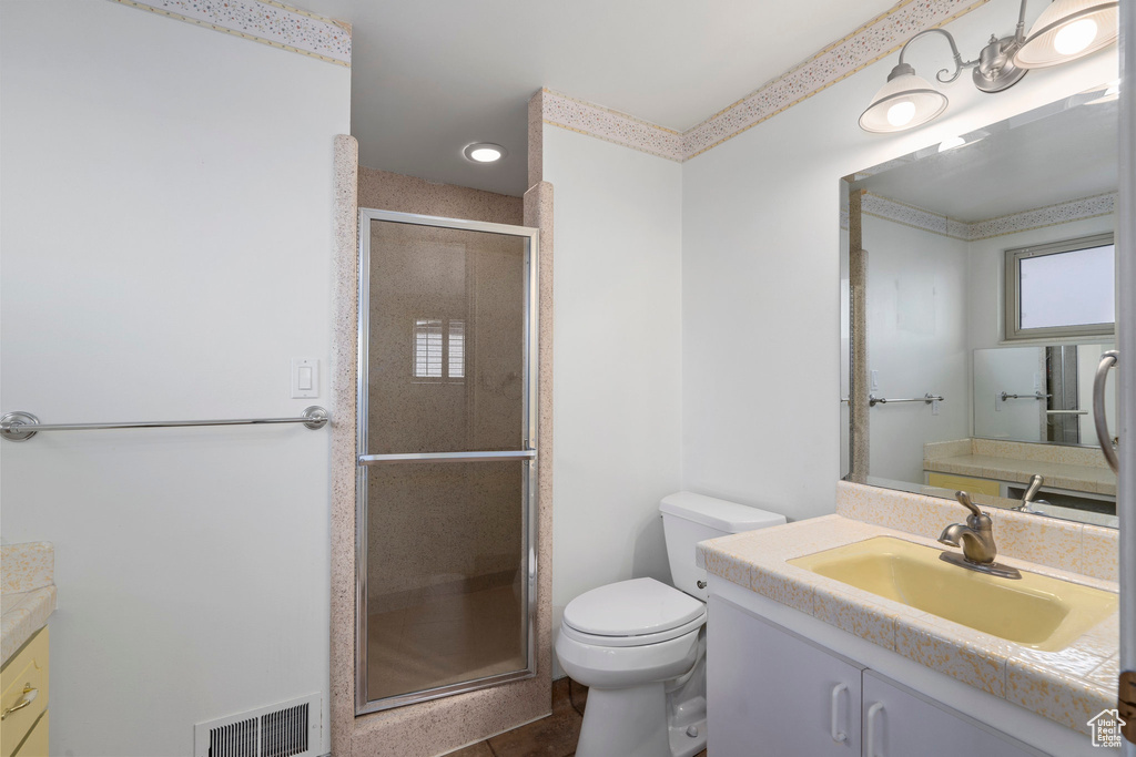 Bathroom featuring tile flooring, a shower with shower door, toilet, and vanity