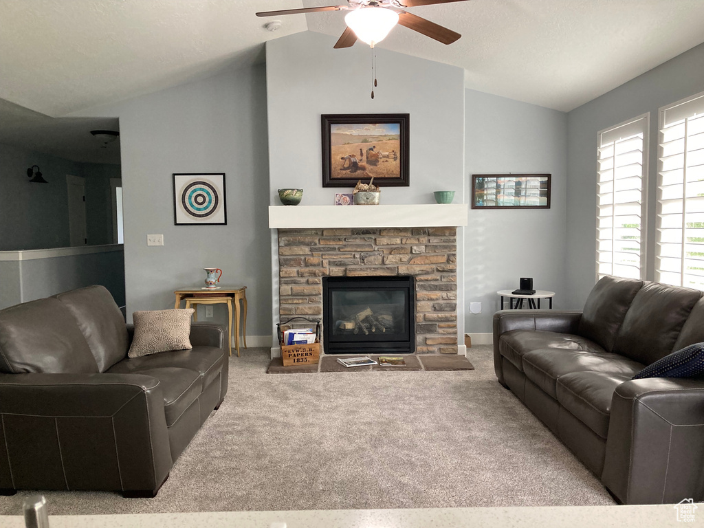Living room with vaulted ceiling, a fireplace, ceiling fan, and light colored carpet