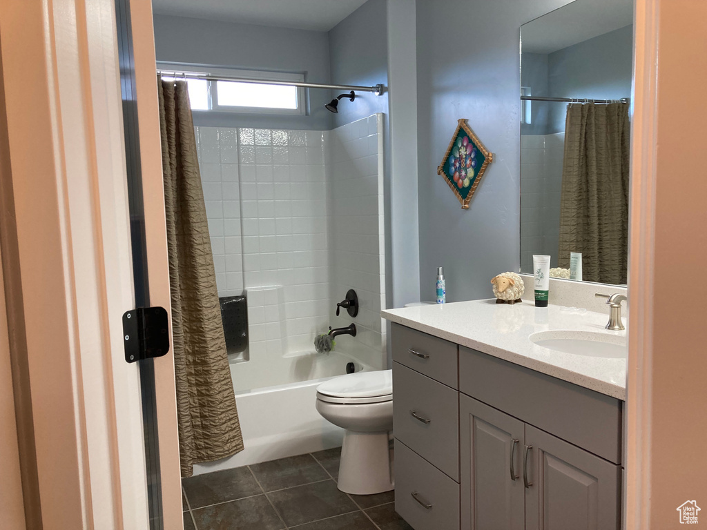 Full bathroom with shower / tub combo with curtain, large vanity, tile flooring, and toilet