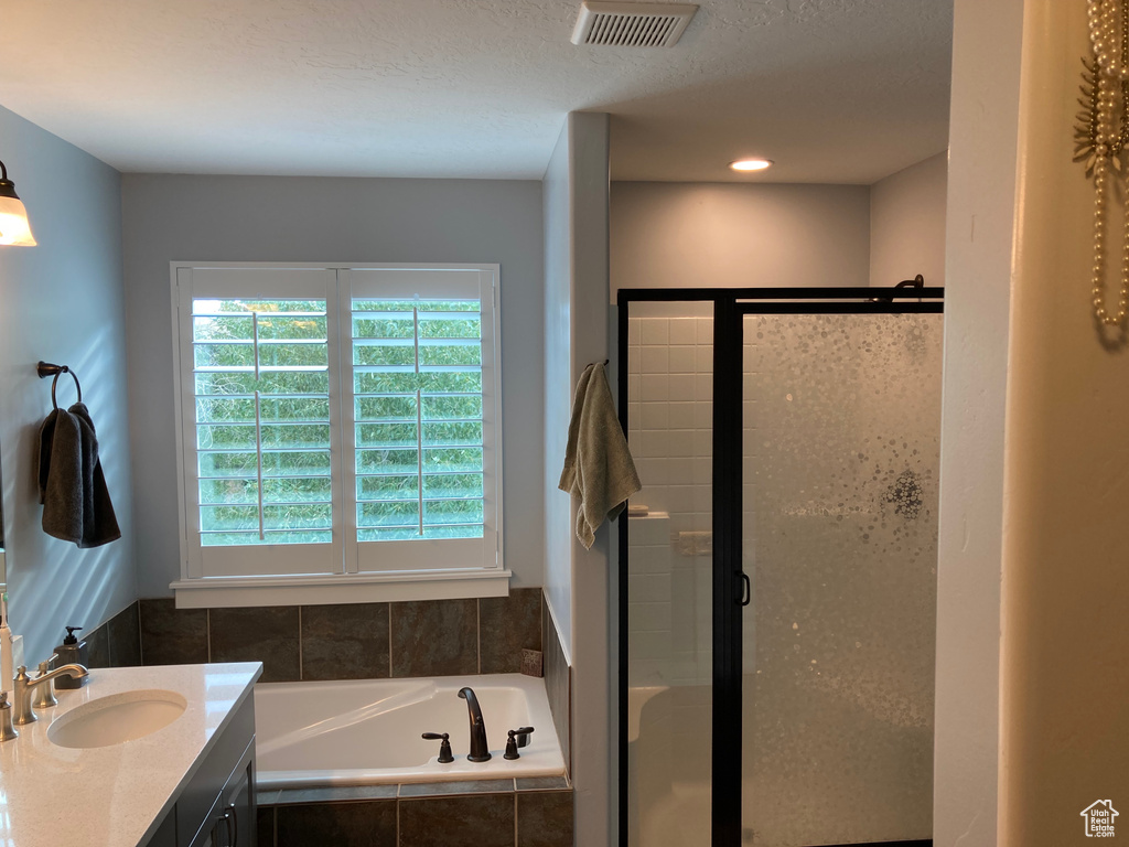 Bathroom featuring vanity, separate shower and tub, and a textured ceiling
