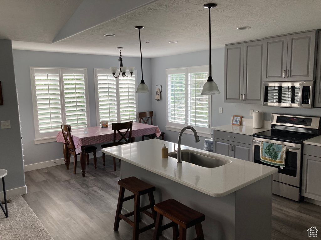 Kitchen with a chandelier, sink, appliances with stainless steel finishes, and hardwood / wood-style flooring