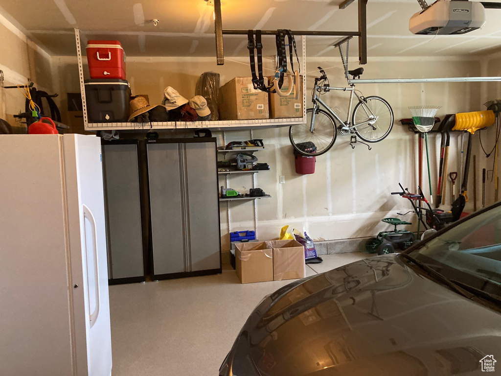 Garage featuring white refrigerator and a garage door opener
