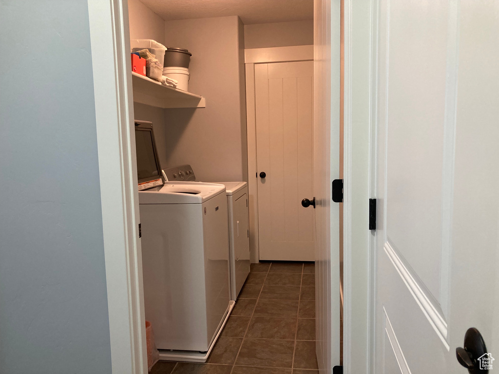 Laundry room featuring dark tile floors and washer and clothes dryer