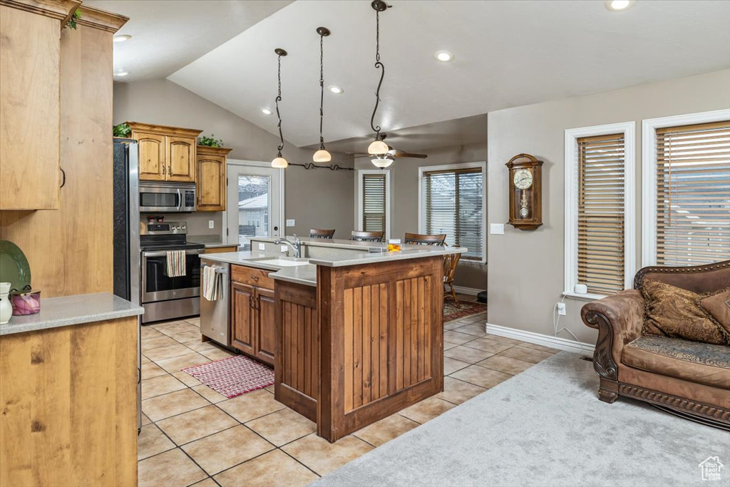 Kitchen with a center island with sink, ceiling fan, light tile floors, stainless steel appliances, and pendant lighting