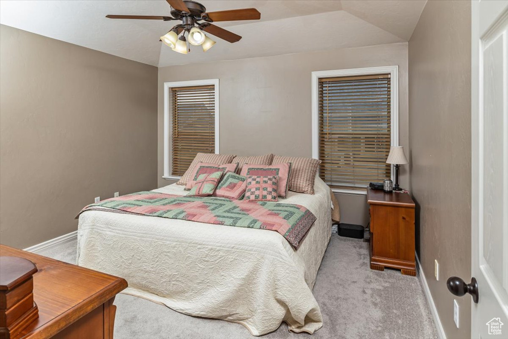 Carpeted bedroom featuring ceiling fan and lofted ceiling