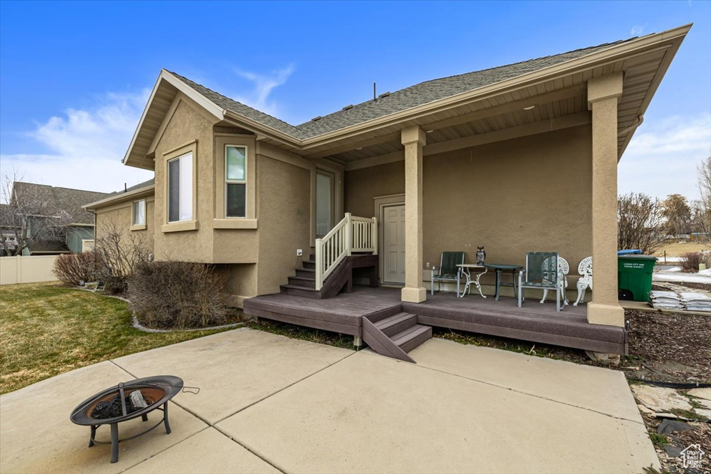 Rear view of property with a wooden deck, a patio area, and a fire pit