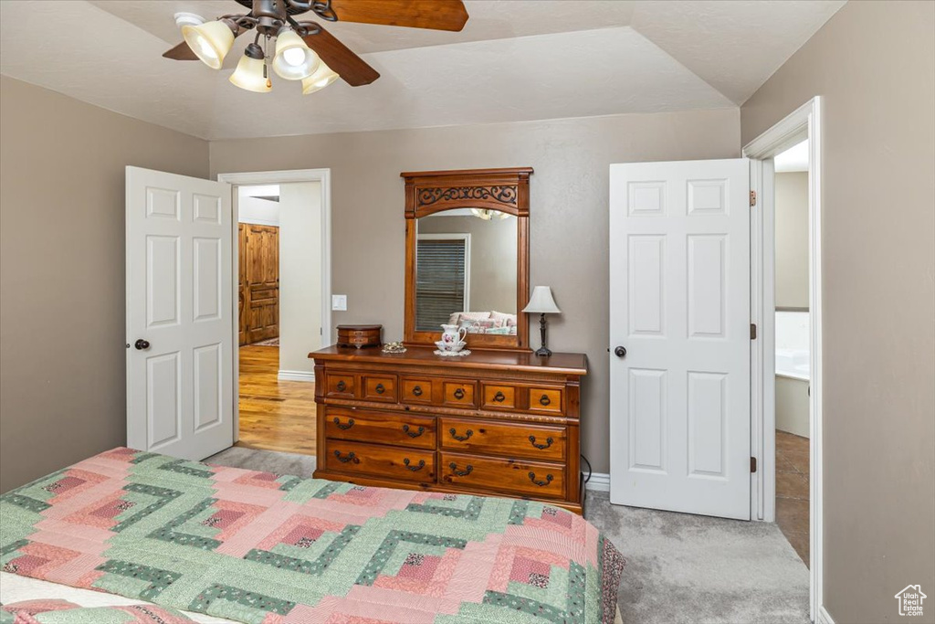 Carpeted bedroom featuring vaulted ceiling and ceiling fan