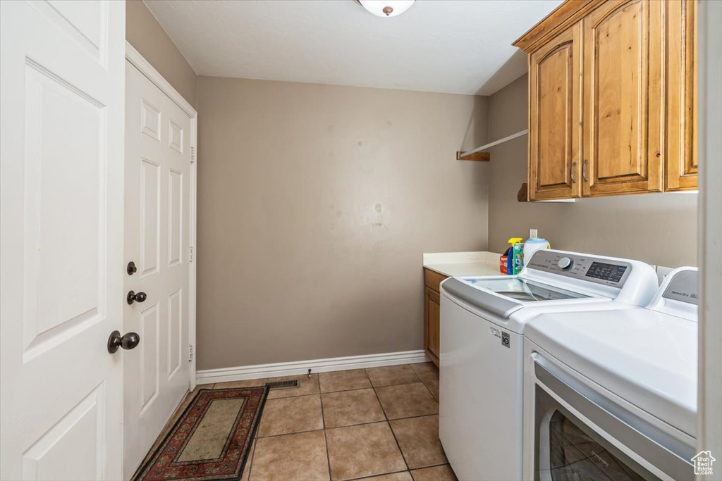 Laundry area featuring light tile floors, cabinets, and independent washer and dryer