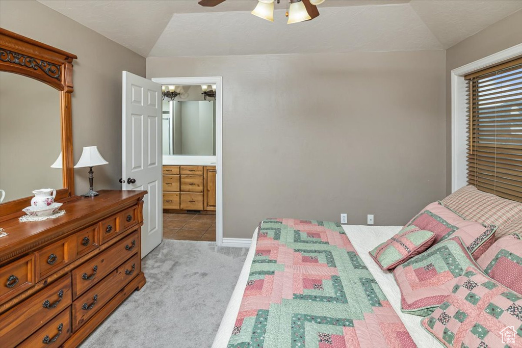 Carpeted bedroom with ceiling fan with notable chandelier and lofted ceiling