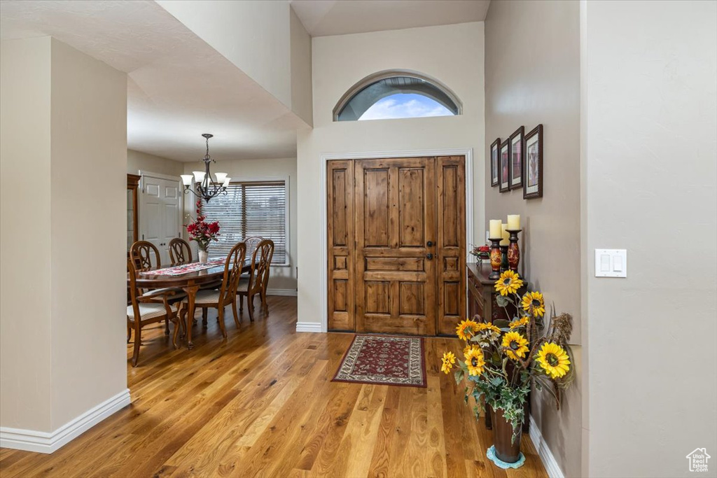 Foyer with an inviting chandelier, a towering ceiling, and light wood-type flooring