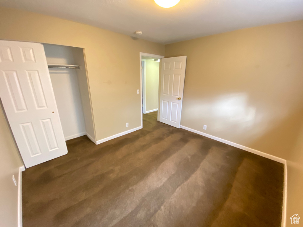 Unfurnished bedroom with dark colored carpet and a closet
