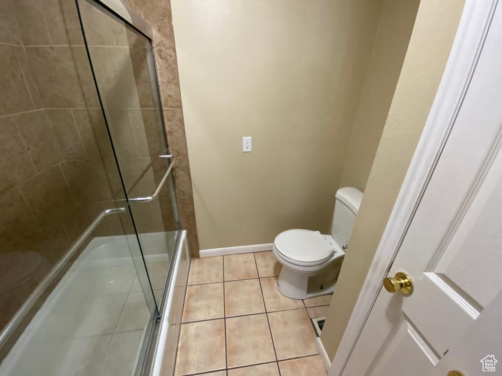 Bathroom with a shower with door, tile floors, and toilet