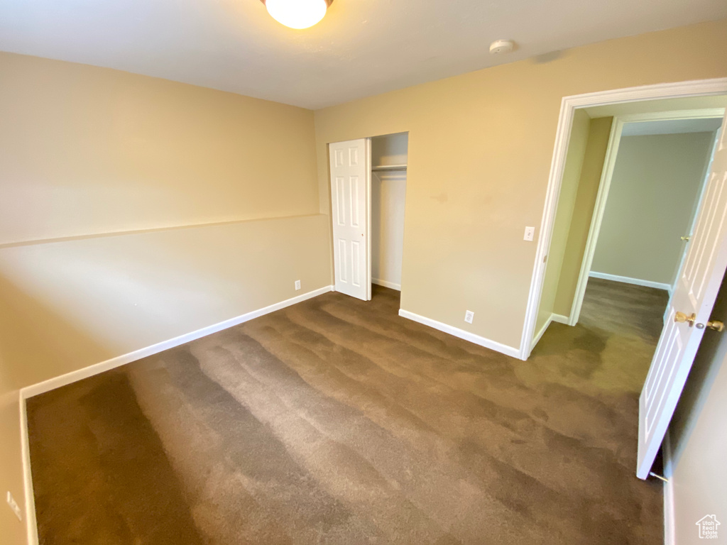 Unfurnished bedroom with dark carpet and a closet