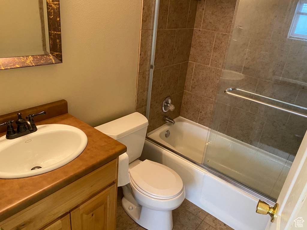 Full bathroom with vanity, shower / bath combination with glass door, tile floors, and toilet
