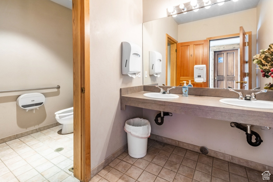Bathroom featuring toilet, tile flooring, and dual sinks