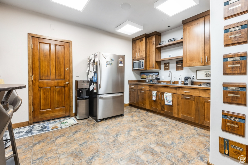 Kitchen with light tile flooring, sink, and stainless steel appliances