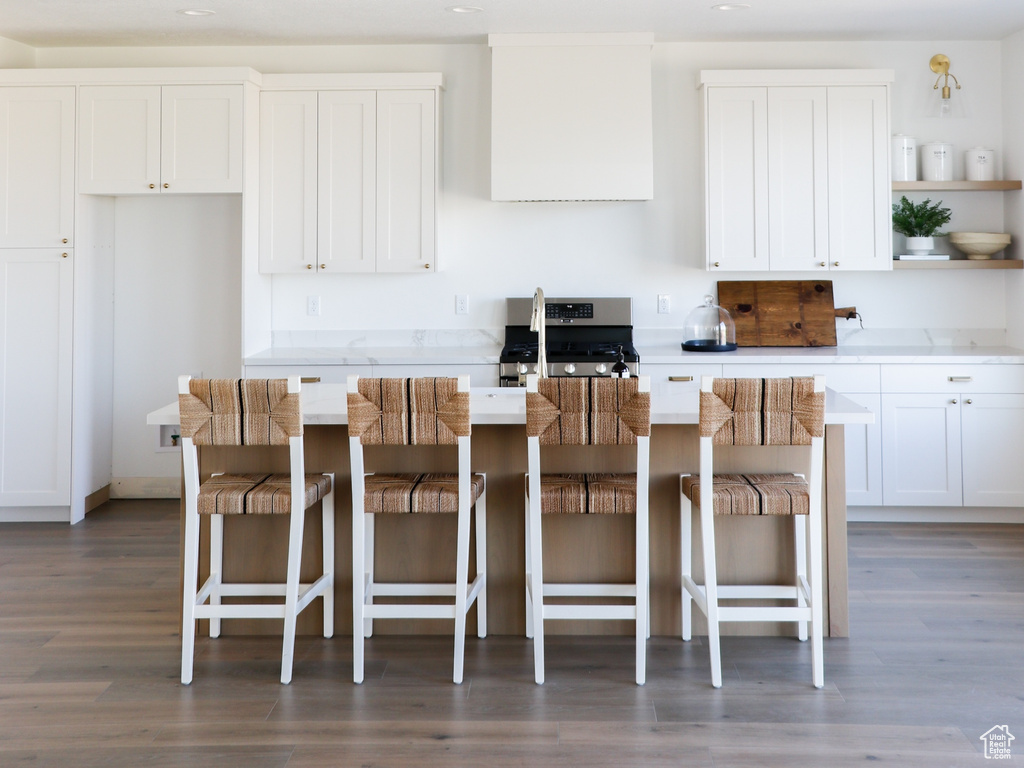 Kitchen featuring dark wood-type flooring, a breakfast bar area, and white cabinets