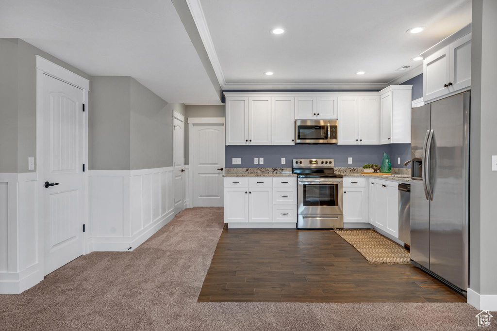 Kitchen featuring light stone countertops, stainless steel appliances, white cabinets, and dark hardwood / wood-style flooring
