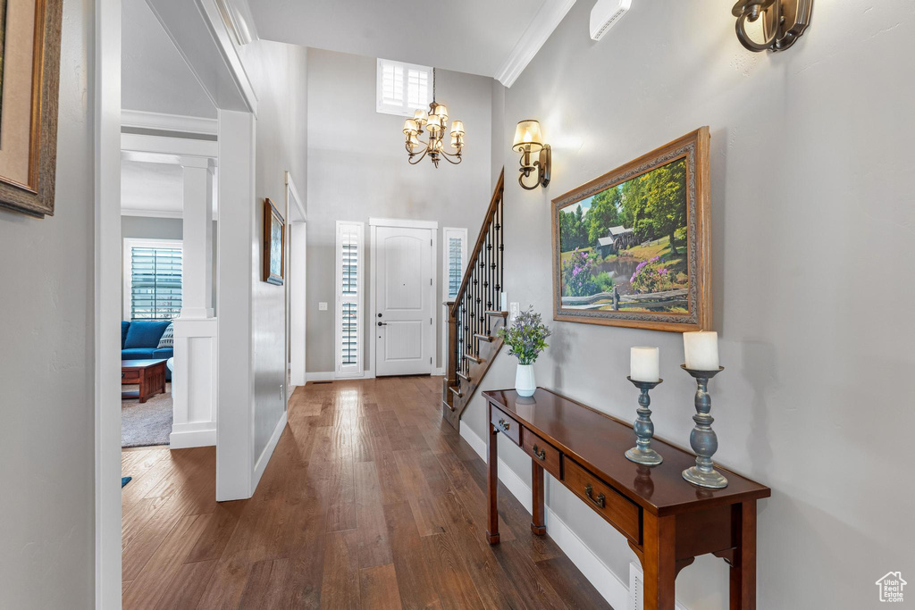 Foyer entrance with a healthy amount of sunlight, crown molding, a notable chandelier, and dark hardwood / wood-style flooring