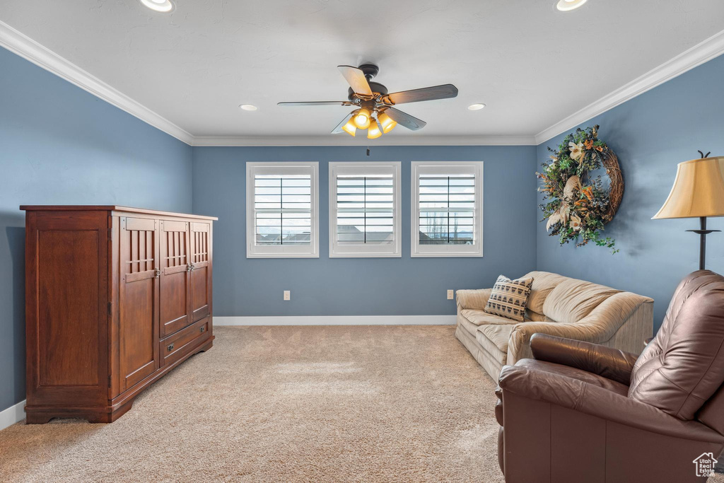 Living room with ceiling fan, light colored carpet, and ornamental molding