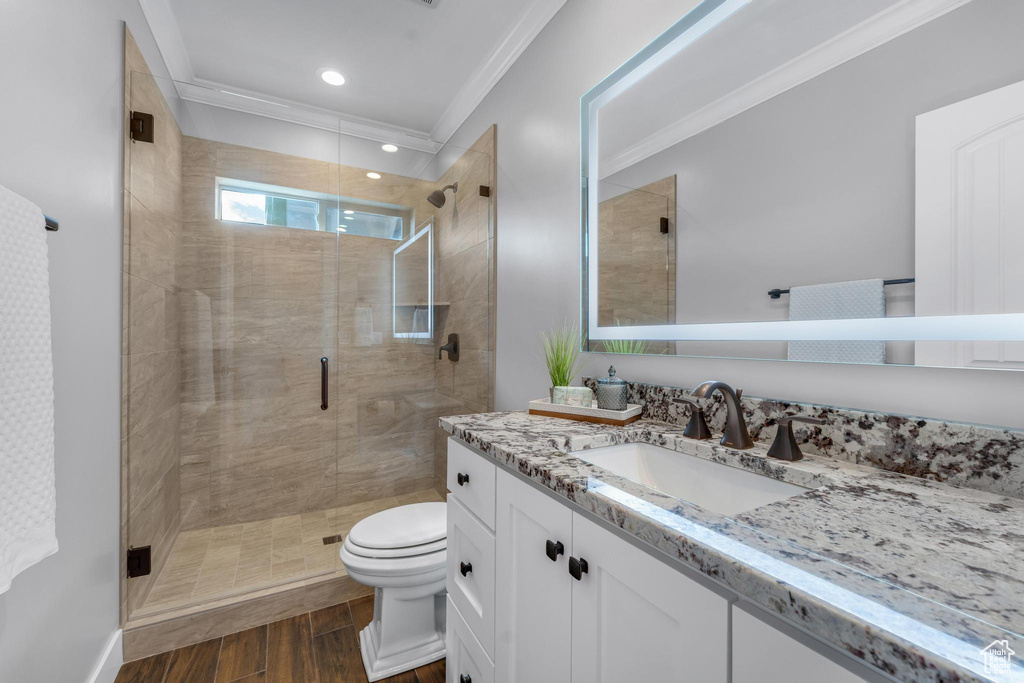 Bathroom featuring an enclosed shower, vanity, crown molding, and toilet