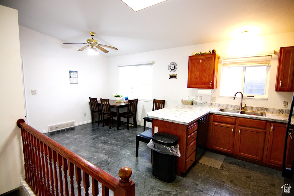 Kitchen with dishwasher, ceiling fan, kitchen peninsula, sink, and dark tile flooring