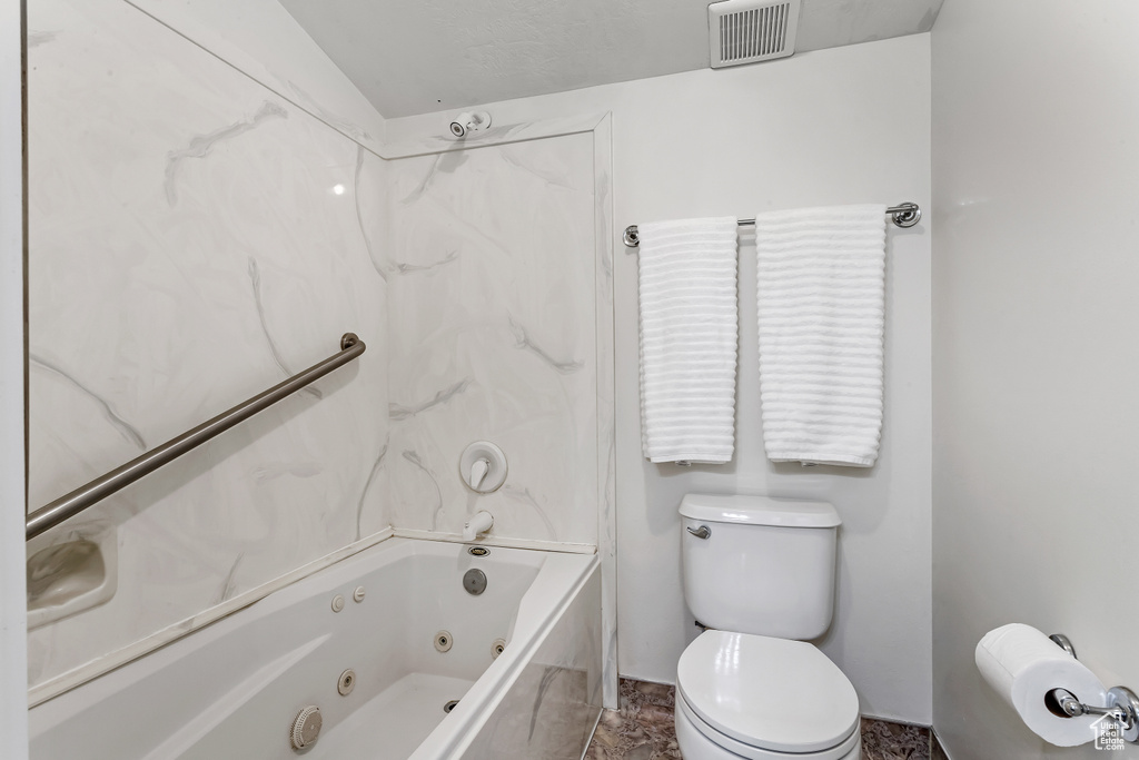 Bathroom with tub / shower combination, tile floors, and toilet