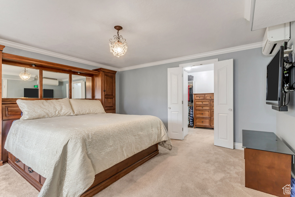 Bedroom with a closet, light colored carpet, crown molding, a wall mounted air conditioner, and a chandelier