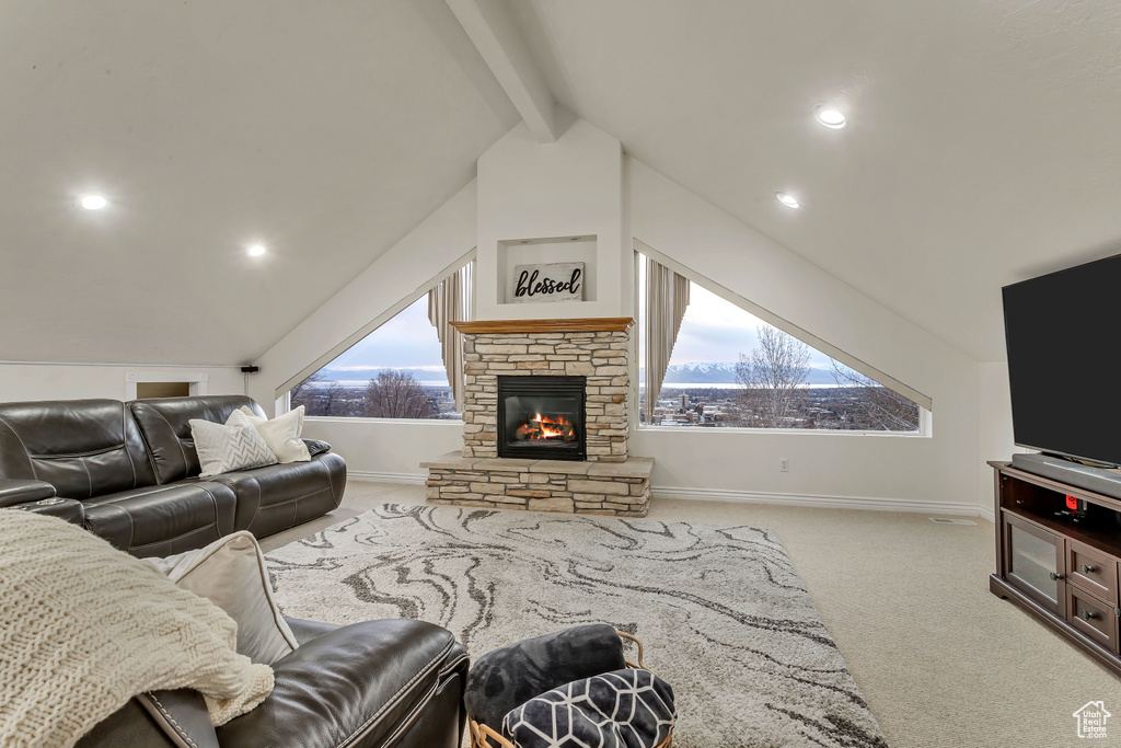 Living room featuring a wealth of natural light, a fireplace, light colored carpet, and lofted ceiling with beams