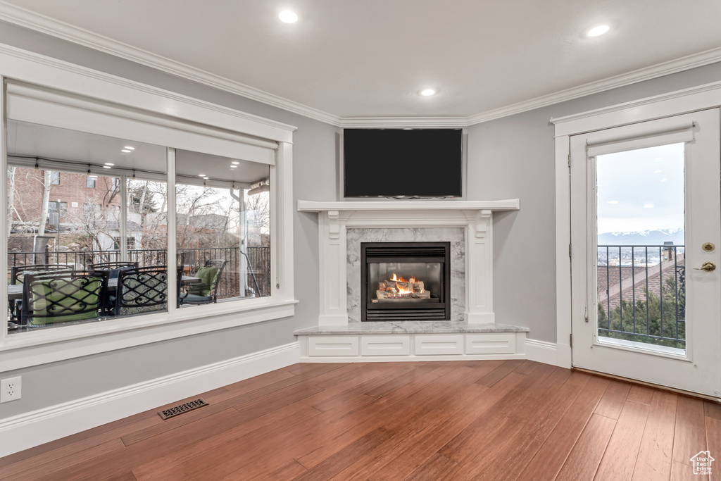 Unfurnished living room featuring a fireplace, crown molding, and hardwood / wood-style flooring